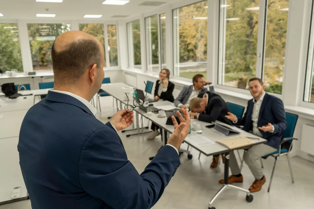 Das Team der Ascensus GmbH hören dem Sprecher nur abgelenkt zu.